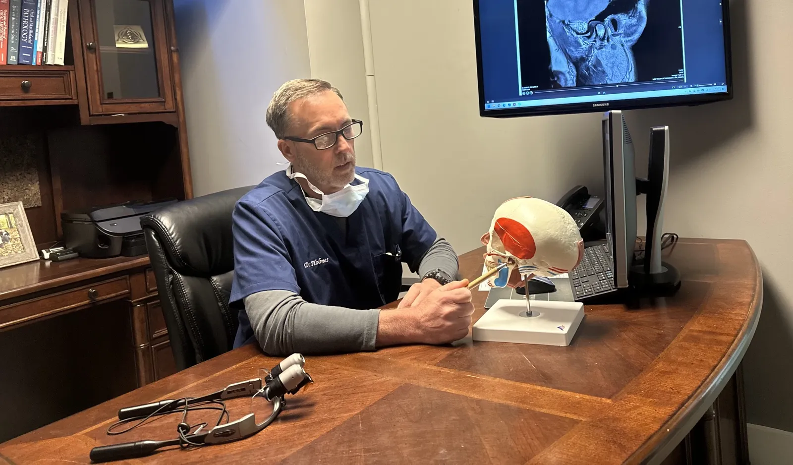 Dr. Dennis M. Holmes reviewing a TMJ MRI with an anatomy model